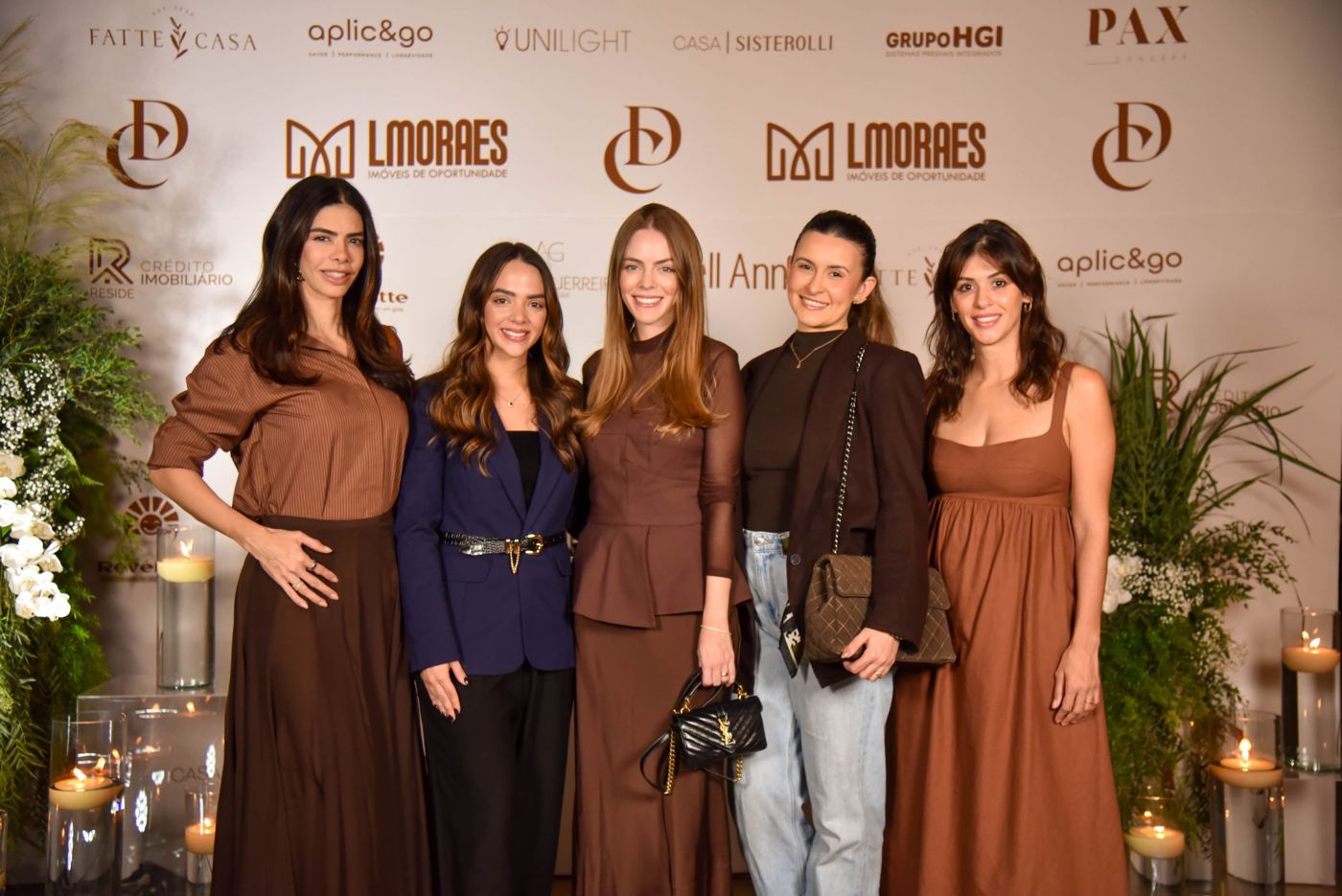 Cinco convidadas posando no painel de fotos