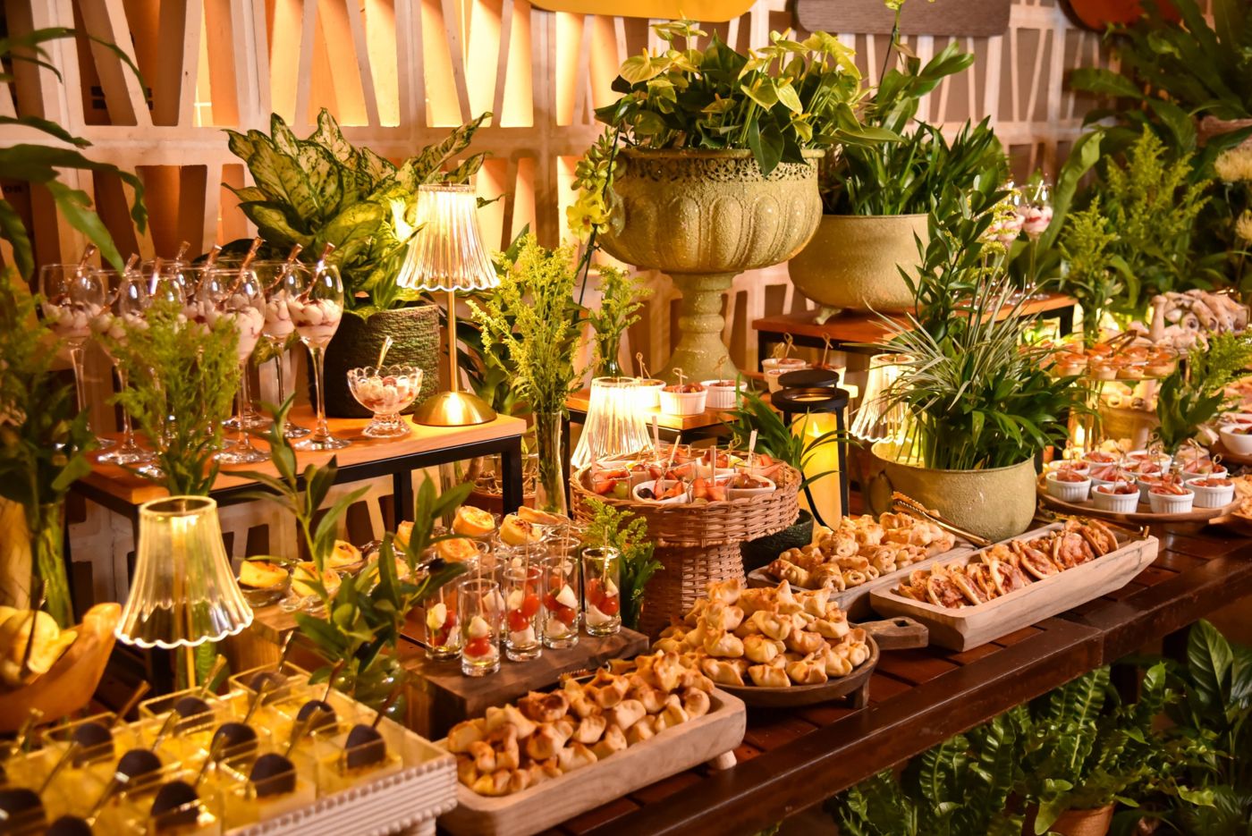 Mesa de buffet com arranjos de plantas e salgados