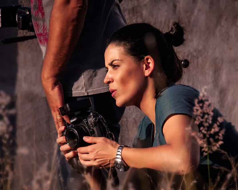 Talita Camargos concentrada, fotografando com uma câmera Nikon